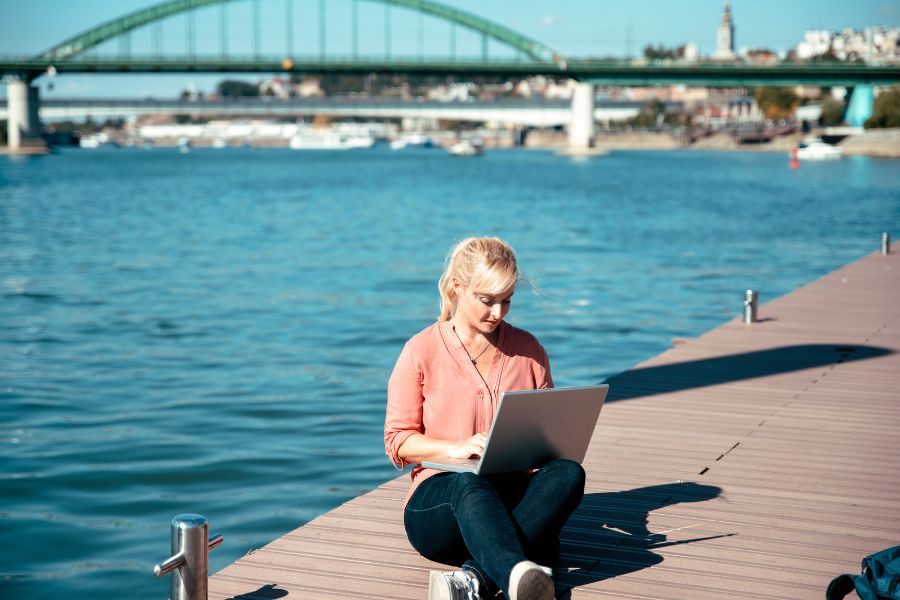 Digital nomad working remotely by water while traveling