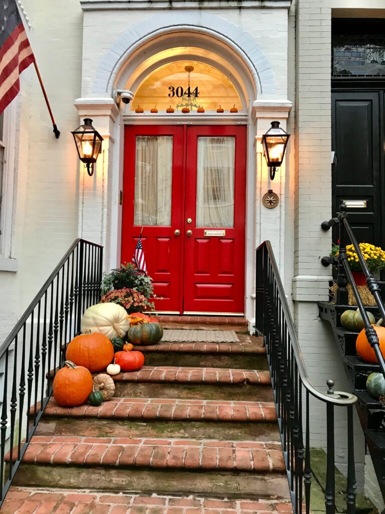 A Washington DC residence with pumpkins on the doorsteps and an American flag.