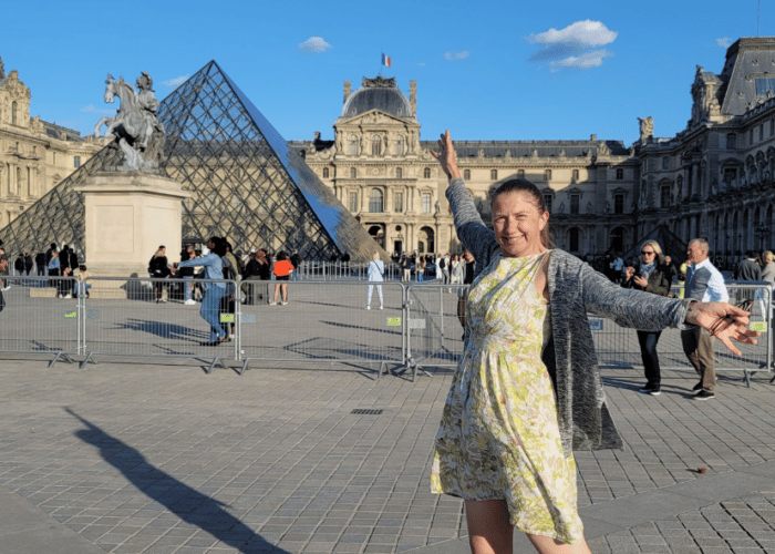 Woman outside Le Louvre Paris with the Text: Why World Vegan Travel is changing its Vaccine Policy
