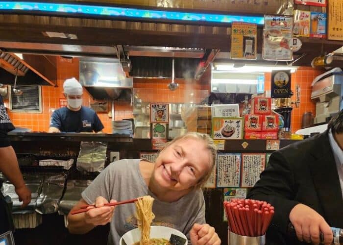 Woman eating Ramen with text: Vegan Delights in Tokyo: Exploring the best plant-based restaurants in the bustling Metropolis