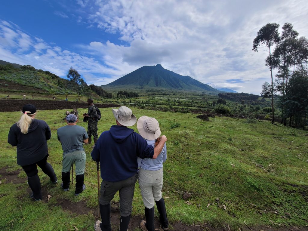 World Vegan Travel group trekking in Rwanda with guide, looking at Volcanoes National Park mountains