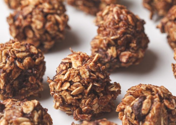 A close-up of easy vegan power balls made with oats and dates, shown on a white surface.