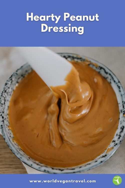 A bowl of creamy peanut dressing being stirred with a spoon.