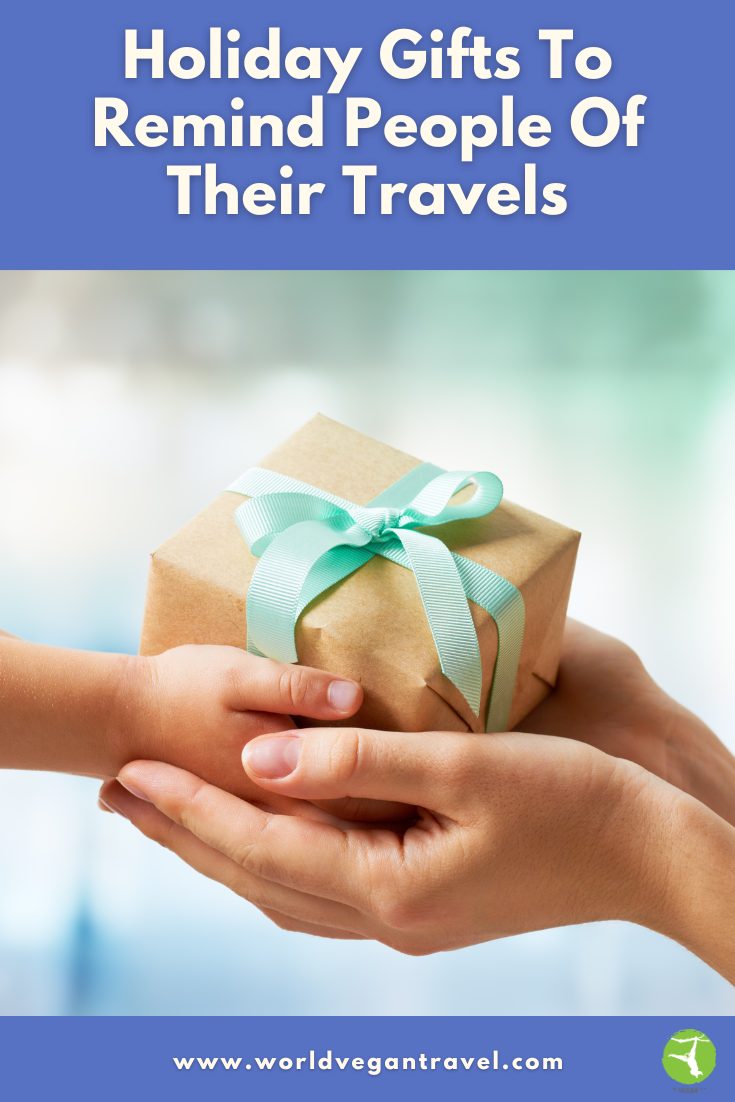 Hands exchanging a wrapped holiday gift with a blue ribbon – World Vegan Travel blog