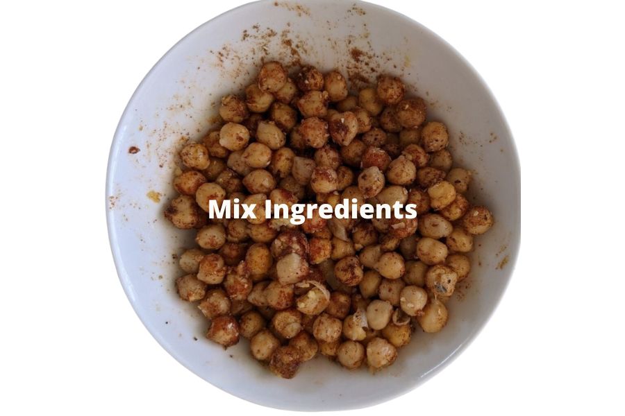 Chickpeas mixed with spices and oil in a bowl before baking.
