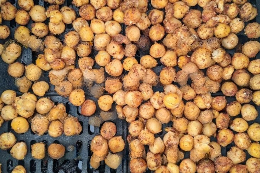 Seasoned chickpeas baking until crispy on an oven or air fryer tray.