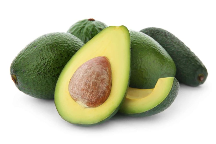Fresh ripe avocados, whole and halved, showing creamy centers, World Vegan Travel.