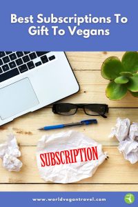 A laptop, plant, glasses, and a crumpled paper labeled “subscription,” showing the idea of choosing the best subscriptions to gift to vegans.