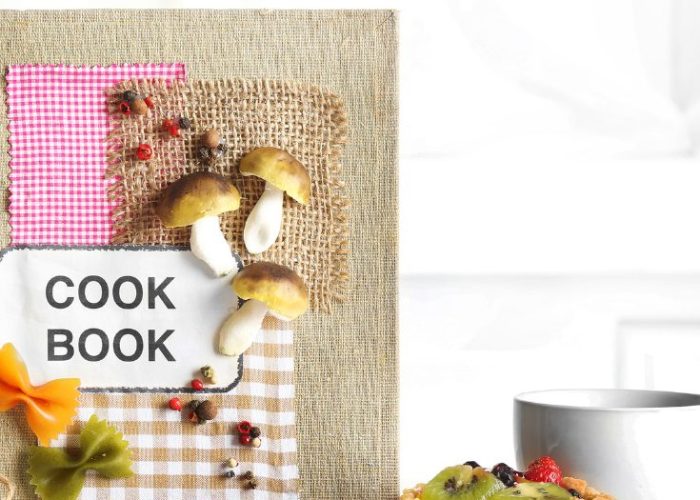 Vegan cookbook surrounded by fresh fruit, a tart, and a cup of coffee — the perfect inspiration for Thanksgiving and Christmas cooking.