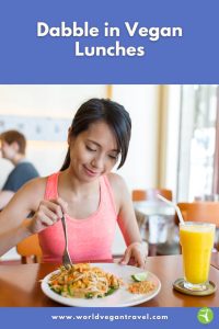 Woman enjoying a colourful vegan lunch with noodles and juice during a relaxing meal, part of World Vegan Travel’s vegan lunch guide.