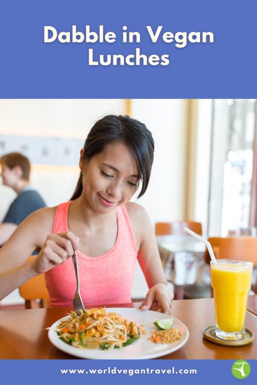 Woman enjoying a colourful vegan lunch with noodles and juice during a relaxing meal, part of World Vegan Travel’s vegan lunch guide.