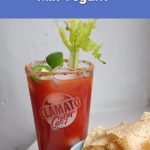 A tall glass of Clamato Caesar mix with celery and lime, showing why traditional Caesar drinks are not vegan.