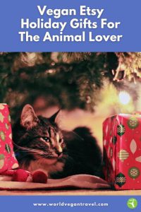 Vegan Etsy holiday gifts for animal lovers – cat resting by Christmas tree with presents.