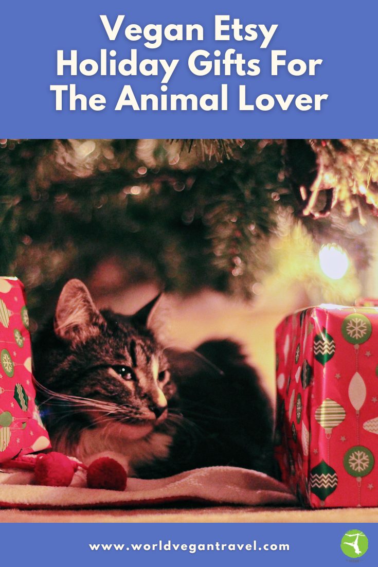 Vegan Etsy holiday gifts for animal lovers – cat resting by Christmas tree with presents.