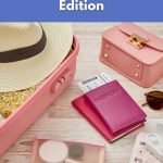 Flat lay of vegan-friendly travel essentials for women, including a pink suitcase, hat, passport, and toiletries.