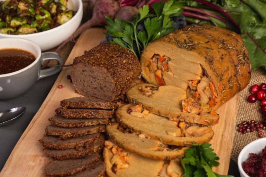 Sliced vegan roast with stuffing from The Very Good Butchers on a wooden board.