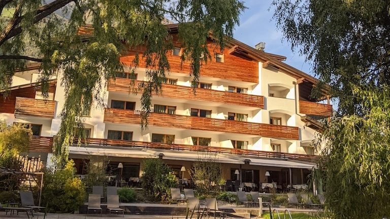 World Vegan Travel vegan hotels in Italy Golden hour. The light is hitting the back of a modern mountain chalet hotel