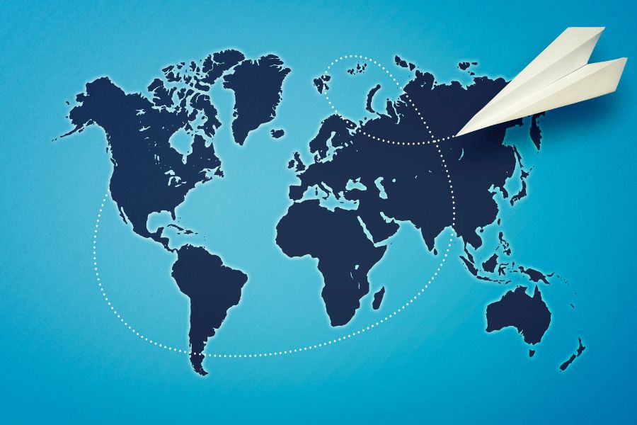 Paper airplane flying across a world map.
