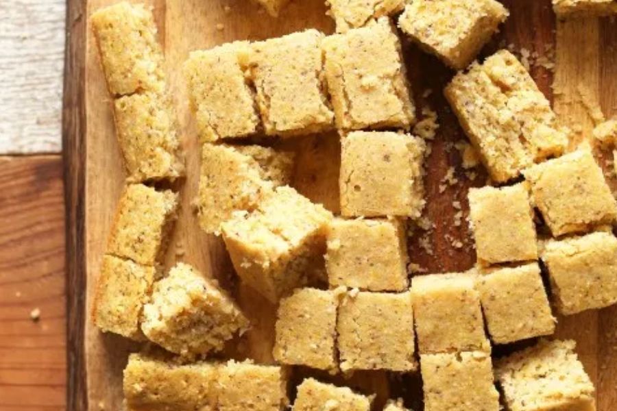 Vegan cornbread cut into squares on a wooden board