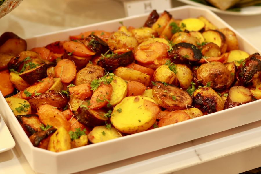 Roasted root vegetables in a tray with herbs