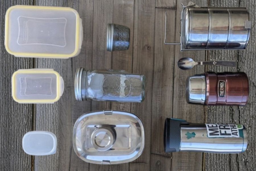 A collection of different lunch containers including jars, stainless steel boxes, and reusable tubs.