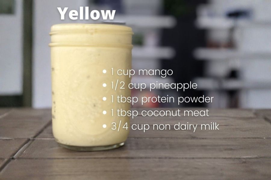 Yellow vegan smoothie in a jar with mango, pineapple, coconut, protein powder, and plant milk recipe.