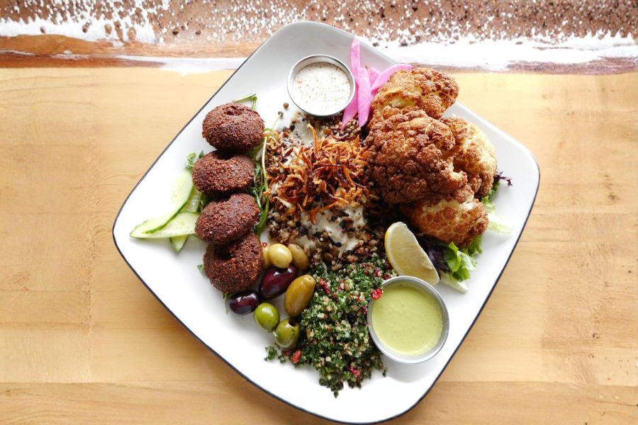 Falafel platter with hummus, cauliflower, and salad — an easy vegan choice at a Middle Eastern restaurant.