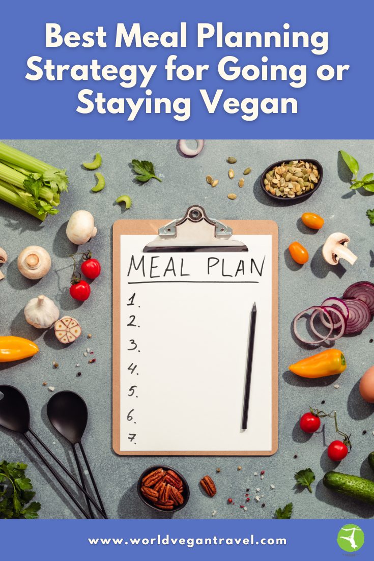 Best Meal Planning Strategy for Going or Staying Vegan | World Vegan Travel Clipboard with a meal plan surrounded by fresh vegetables and ingredients on a kitchen counter.