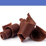 A close-up of smooth dark chocolate curls on a white background.