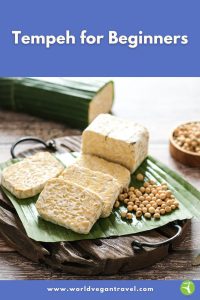 Fresh slices of tempeh on a banana leaf board, ready to cook, for the Tempeh for Beginners guide on World Vegan Travel.