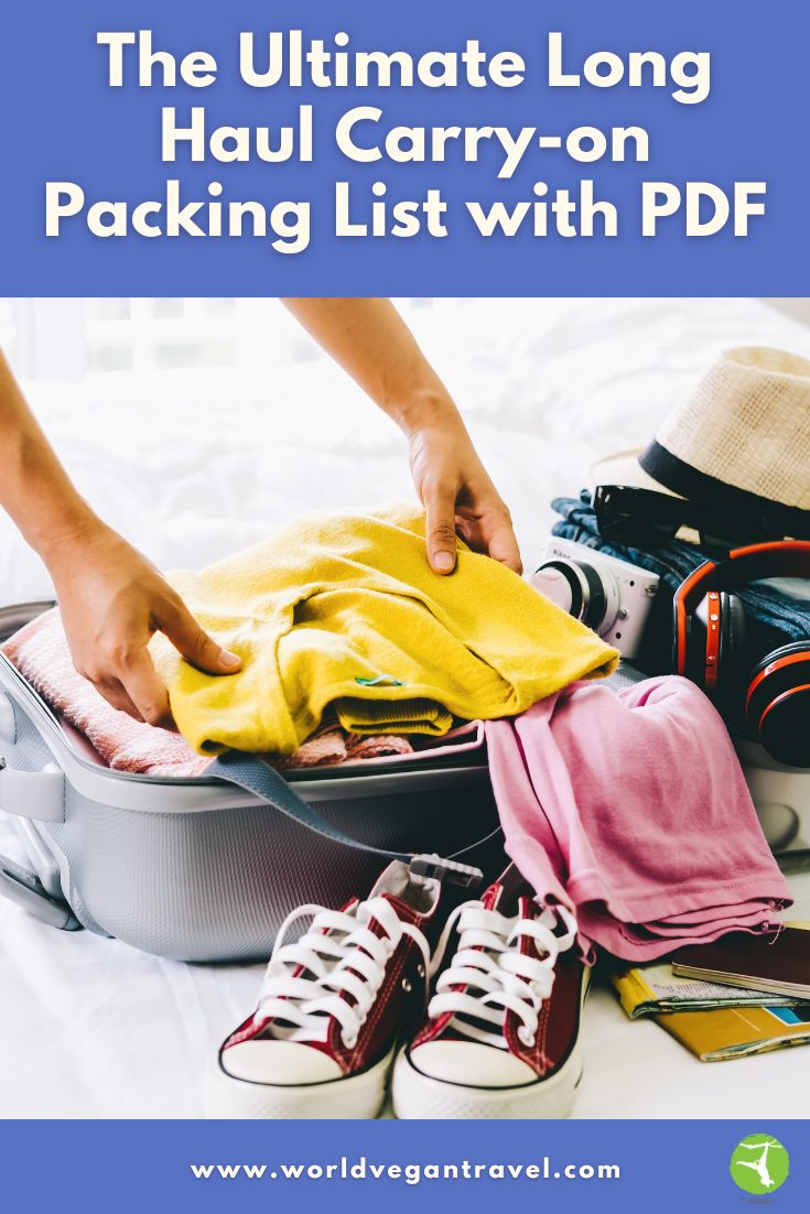 Person packing a yellow sweater into a suitcase with sneakers, camera, and travel essentials — World Vegan Travel carry on packing list.