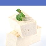 Two blocks of fresh tofu stacked with a mint garnish, perfect for vegan beginners.