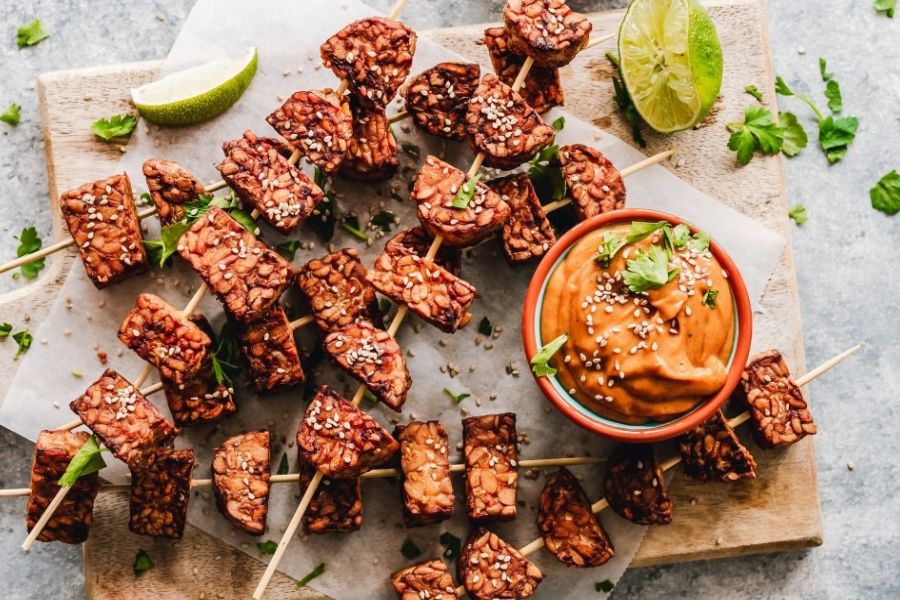 Grilled tempeh skewers with sesame seeds served with a creamy satay dipping sauce.