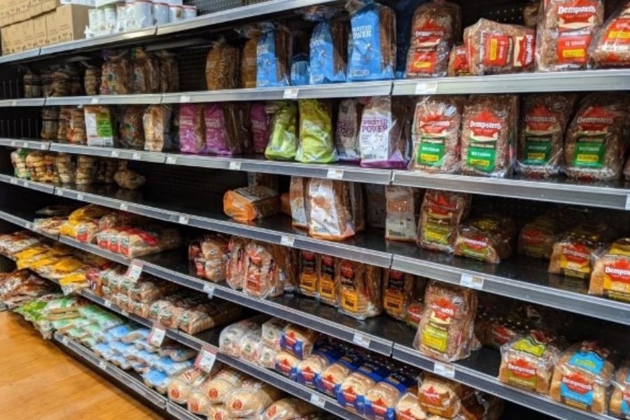 Shelves of artisanal vegan breads and bagels in a grocery store.