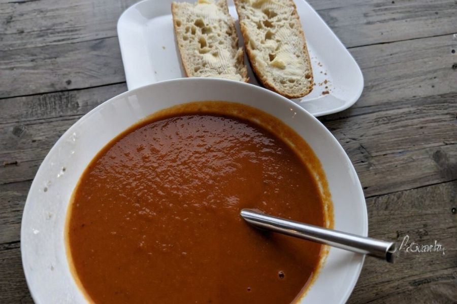 A bowl of rich vegan coconut madras curry soup served with sliced bread.