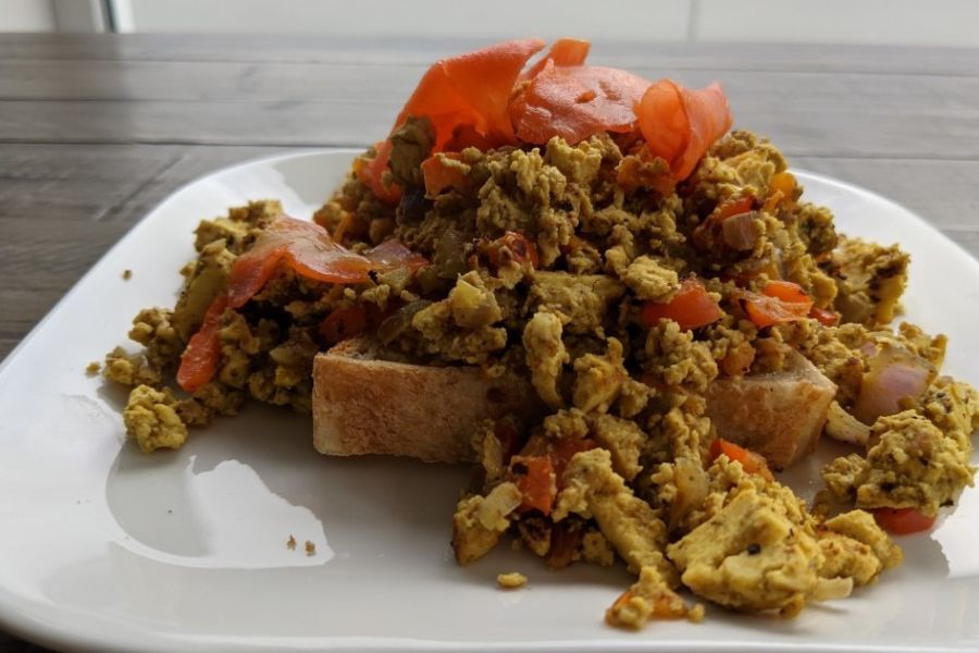 A plate of scrambled tofu with vegetables served on toast.