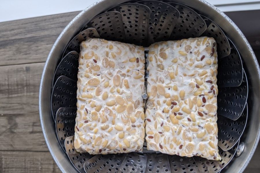 Two blocks of tempeh sitting in a steamer basket ready to be steamed.