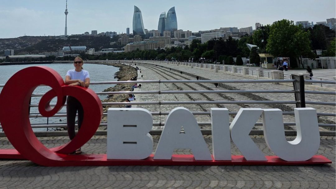 Woman standing in front of I Love Baku sign with Flame Towers in background