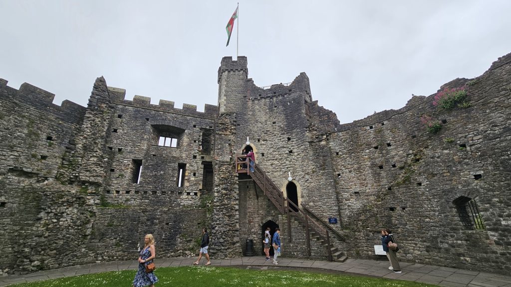 Outside view of Cardiff Castle with stone walls, tower, and Welsh flag