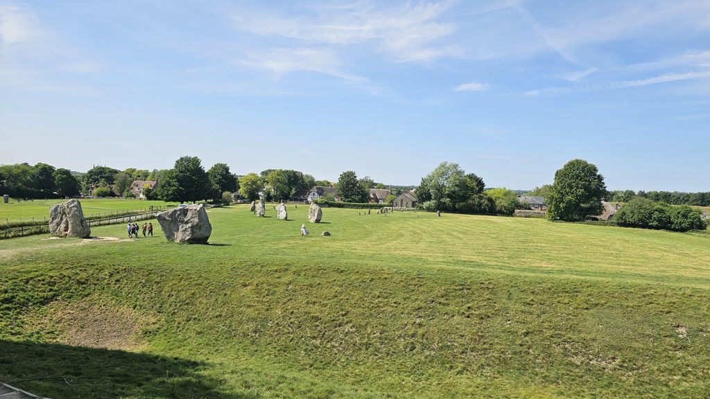 Ancient standing stones at Avebury surrounded by green grass and cottages.