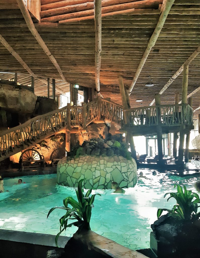 Indoor spa pool with wooden bridges and natural design in Finland.