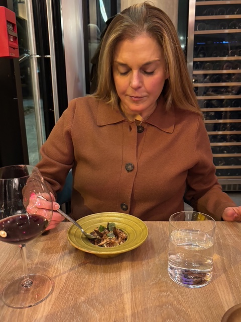 Woman enjoying a plant-based dish with wine at Oyster Oyster in Washington DC.