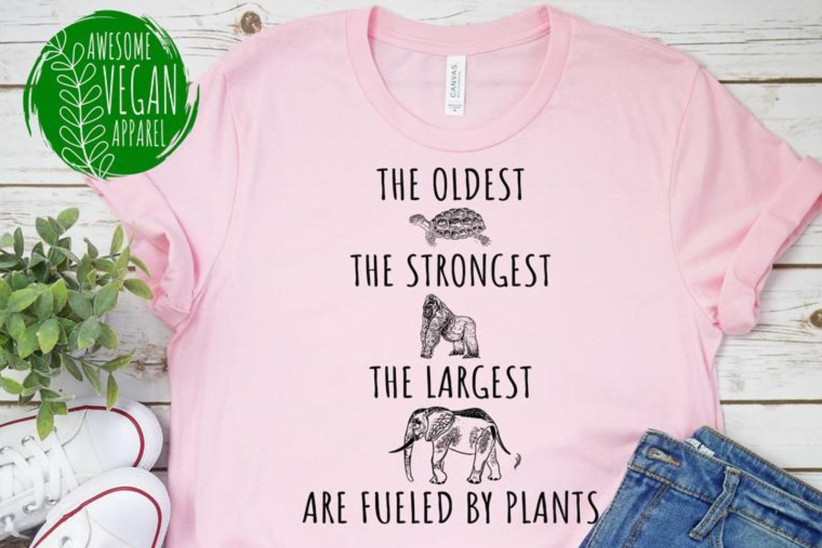 Pink t-shirt with drawings of animals and the words “The oldest, the strongest, the largest are fueled by plants.”