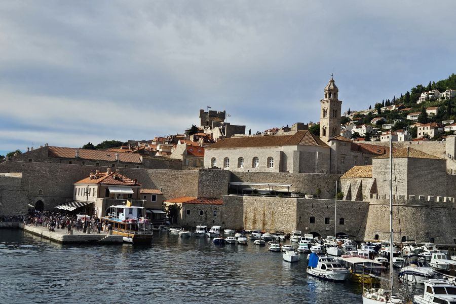 Dubrovnik harbor with stone walls, boats, and terracotta rooftops.