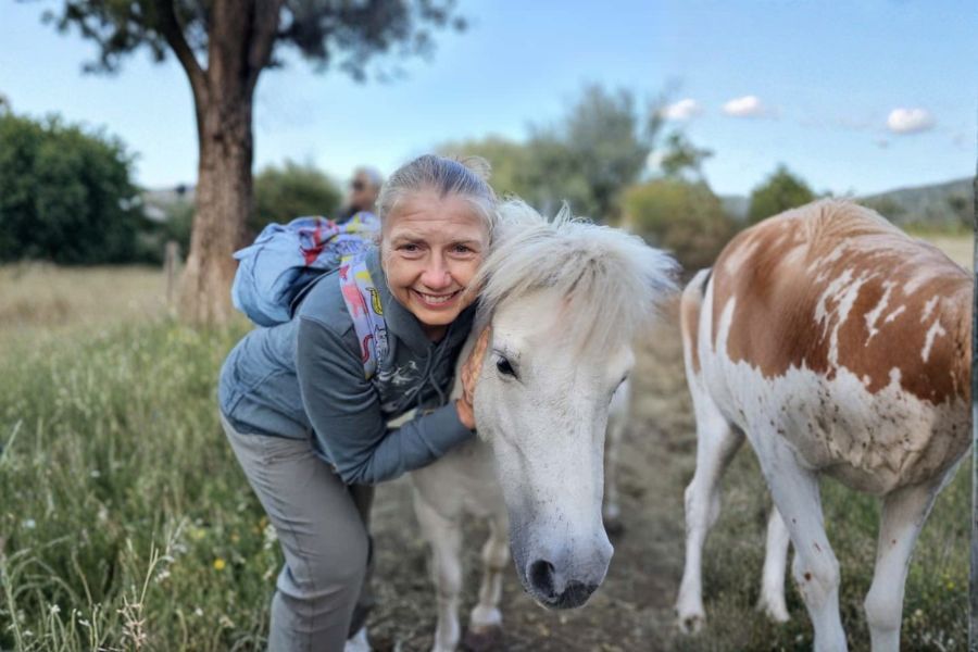 Brighde hugging a rescued white horse at the Brač Animal Sanctuary in Croatia.