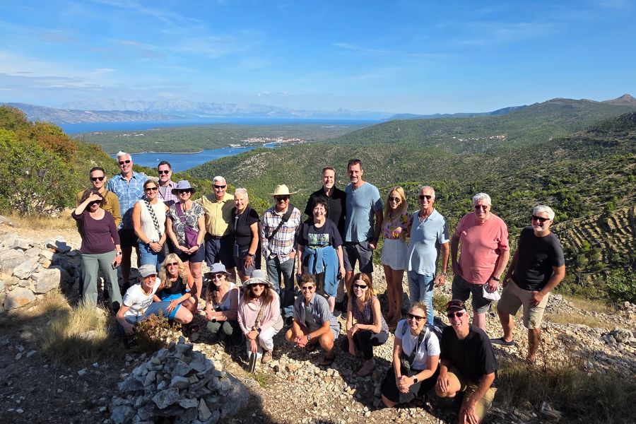 Group of vegan travelers on a hilltop above Stari Grad with views of the sea and islands.