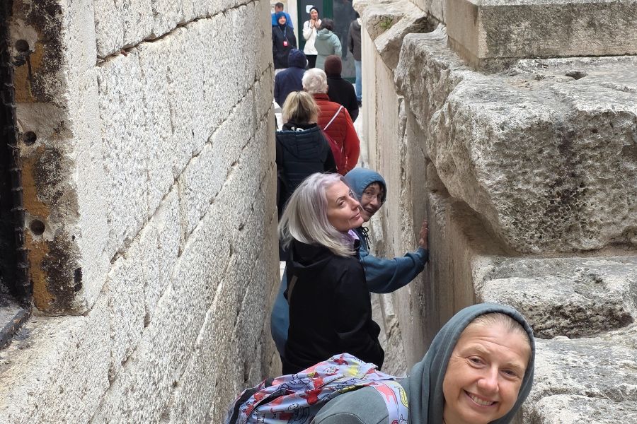 Travelers exploring a narrow stone passage inside Diocletian’s Palace in Split.