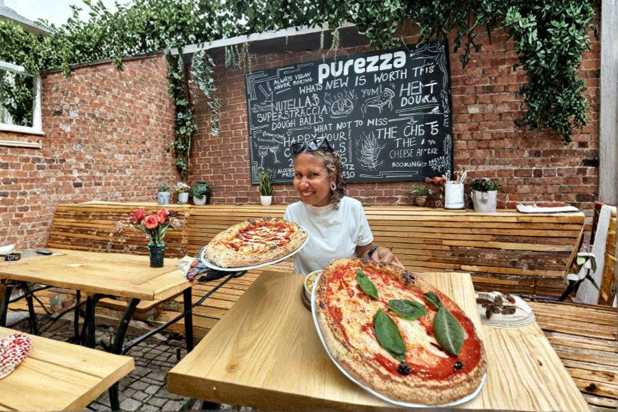 Carla holding vegan pizzas at a vegan pizzeria in London