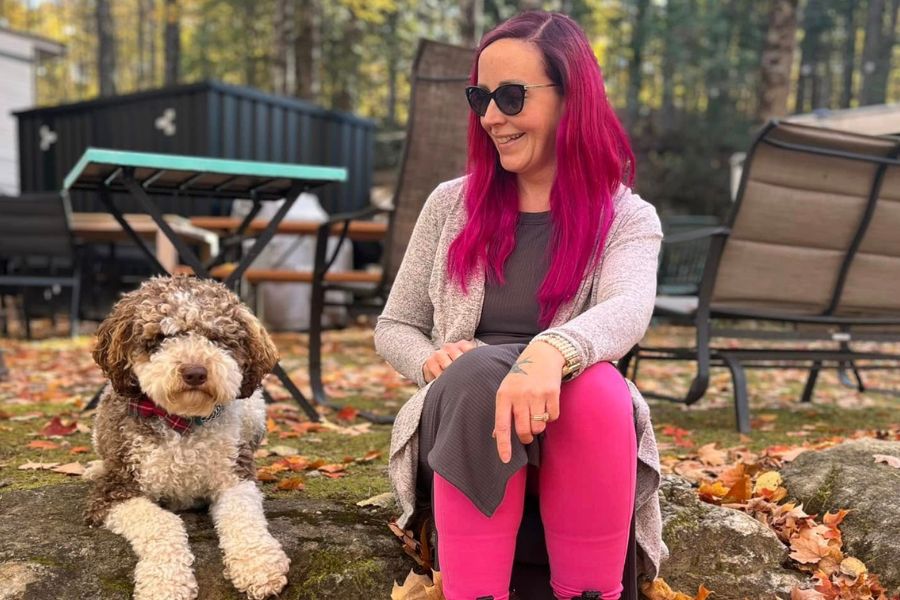 Vegan travel planner Karine Lang relaxing outdoors with her allergy-alert service dog