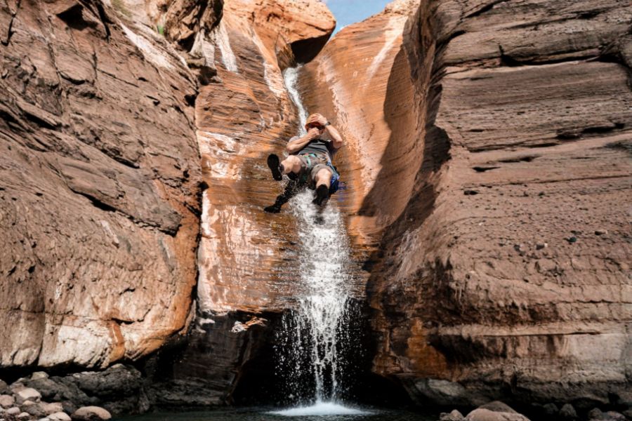 Person sliding down a natural rock waterfall in Karijini National Park